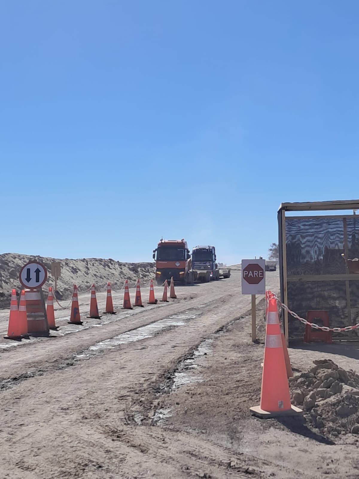 Convoy de camiones aproximándose a punto de control con señalética de PARE